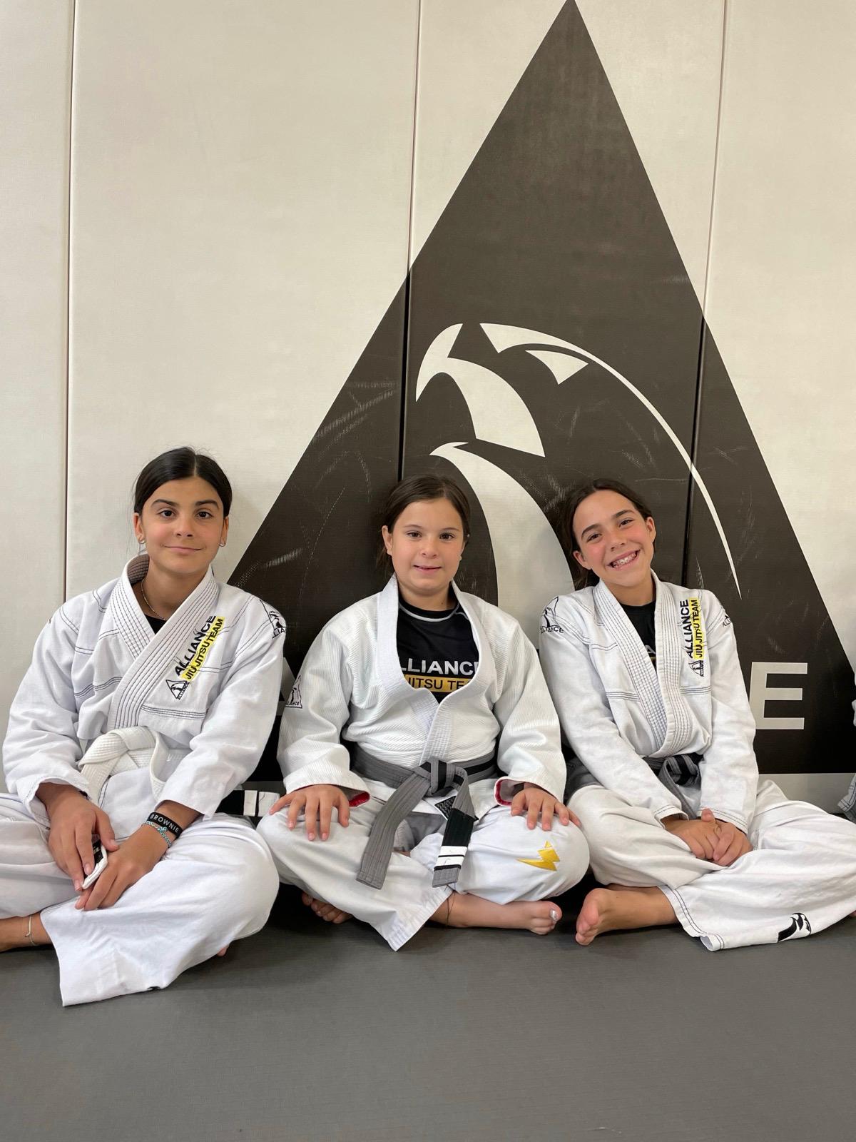 Three young students in front of the Alliance eagle wall