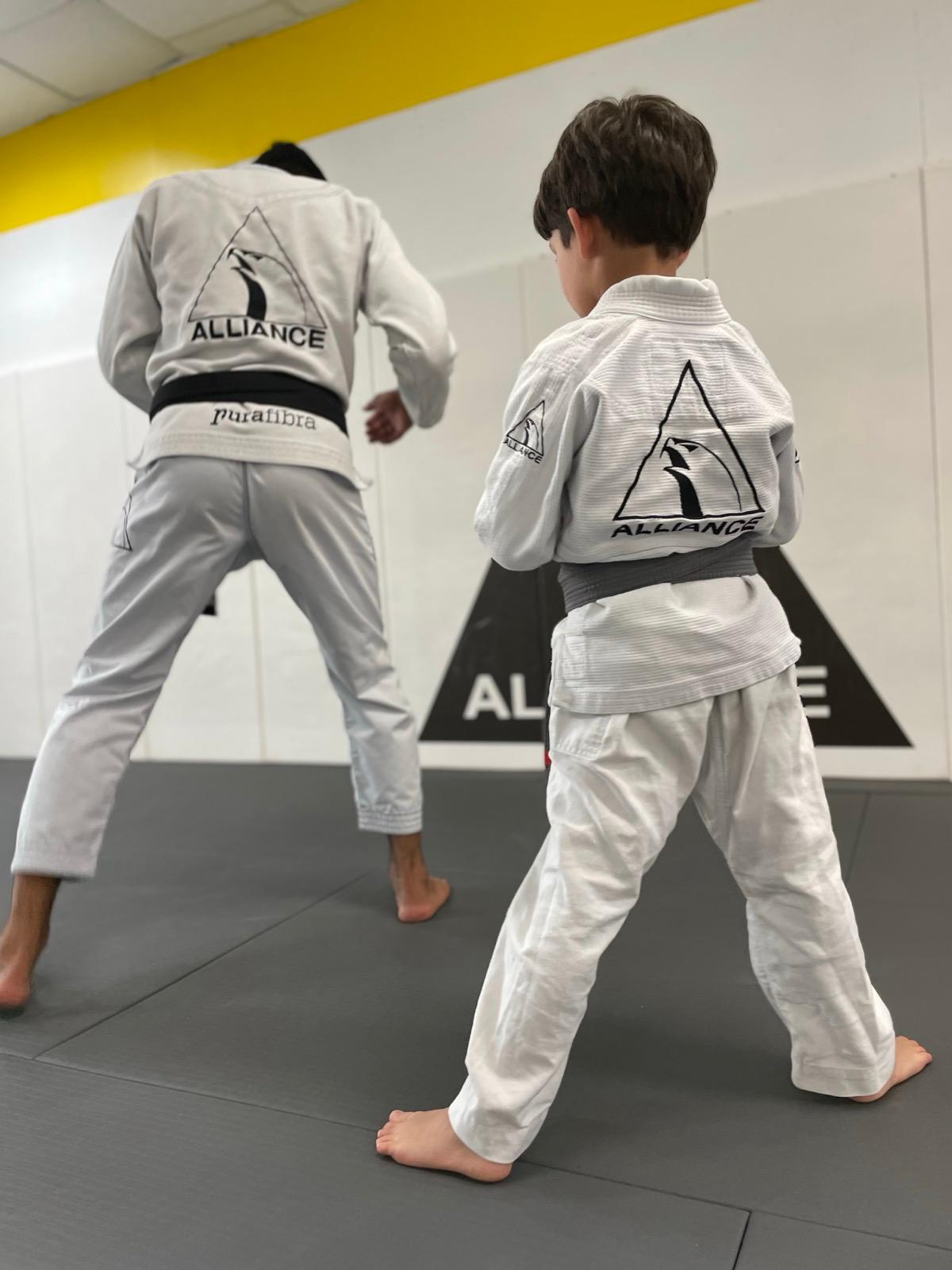 Student drilling technique with an instructor on the mat